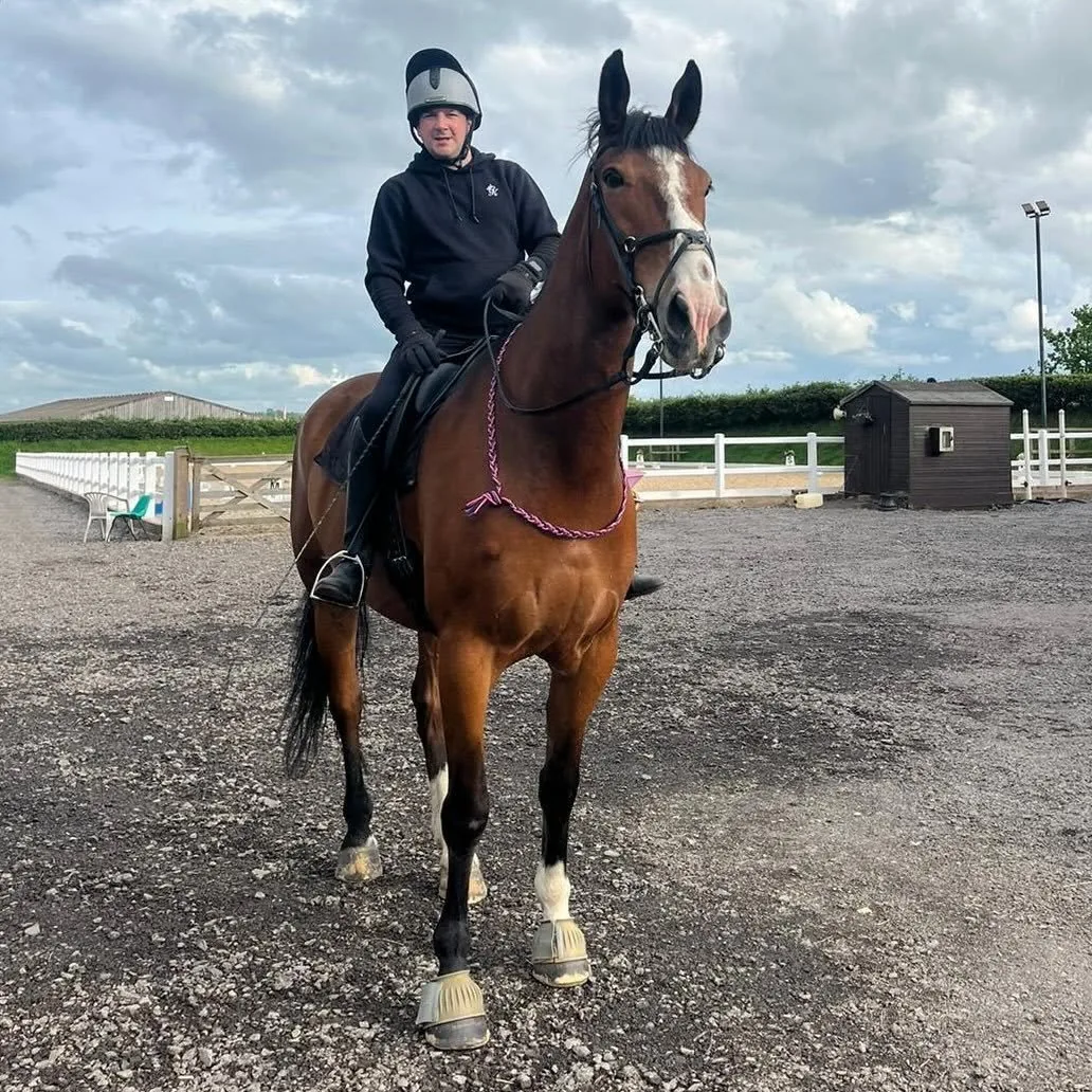 Matt riding a bay horse in an arena